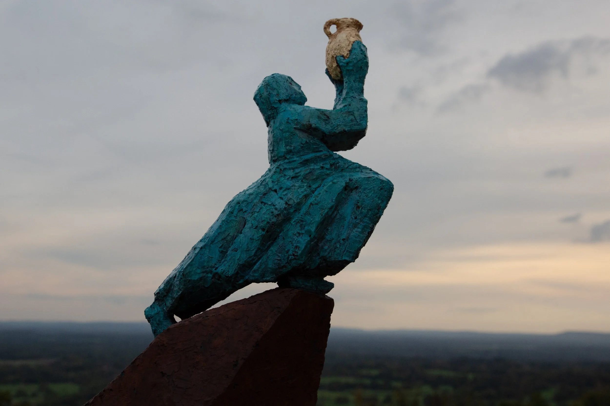 Bronze public sculpture of a woman holding a vessel